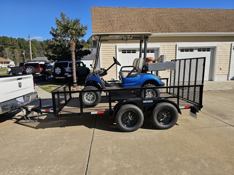 Utility trailer hauling a golf cart